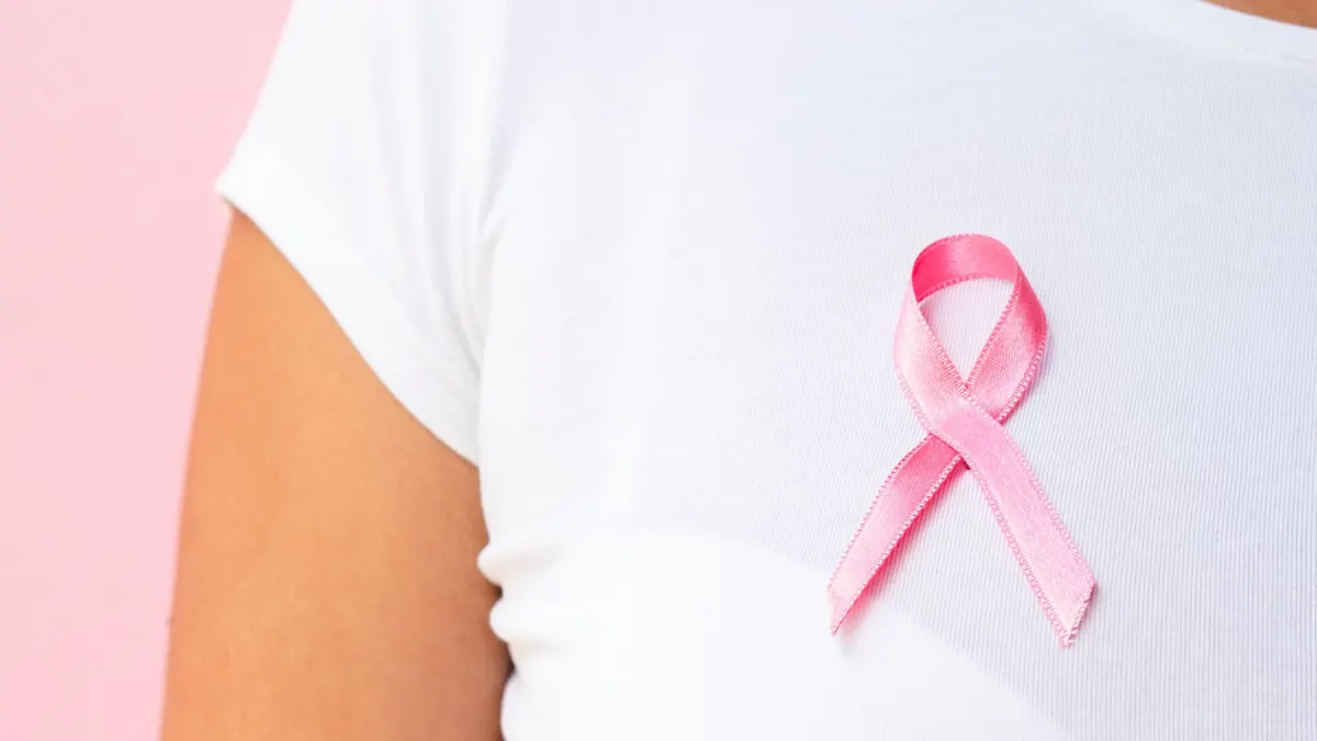 mulher com camiseta branca com fita rosa do cancer de mama