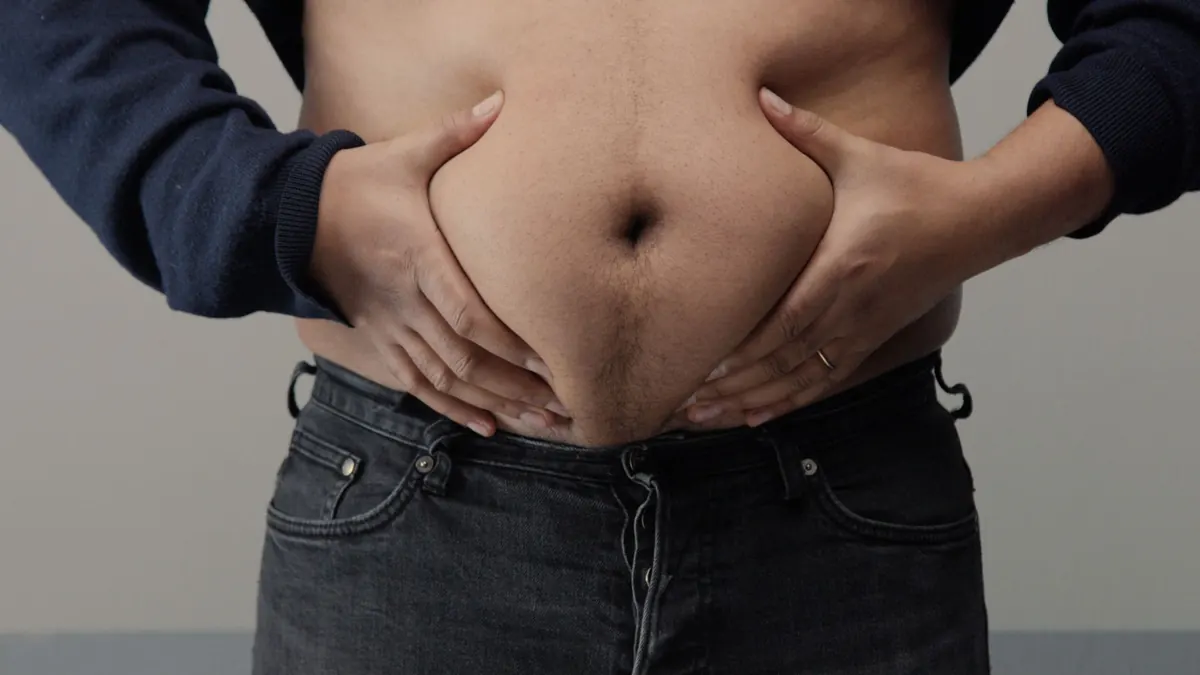 Homem acima do peso segurando gordura abdominal