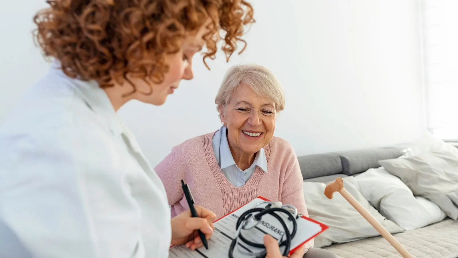 Médica conversando com paciente idosa em atendimento domiciliar