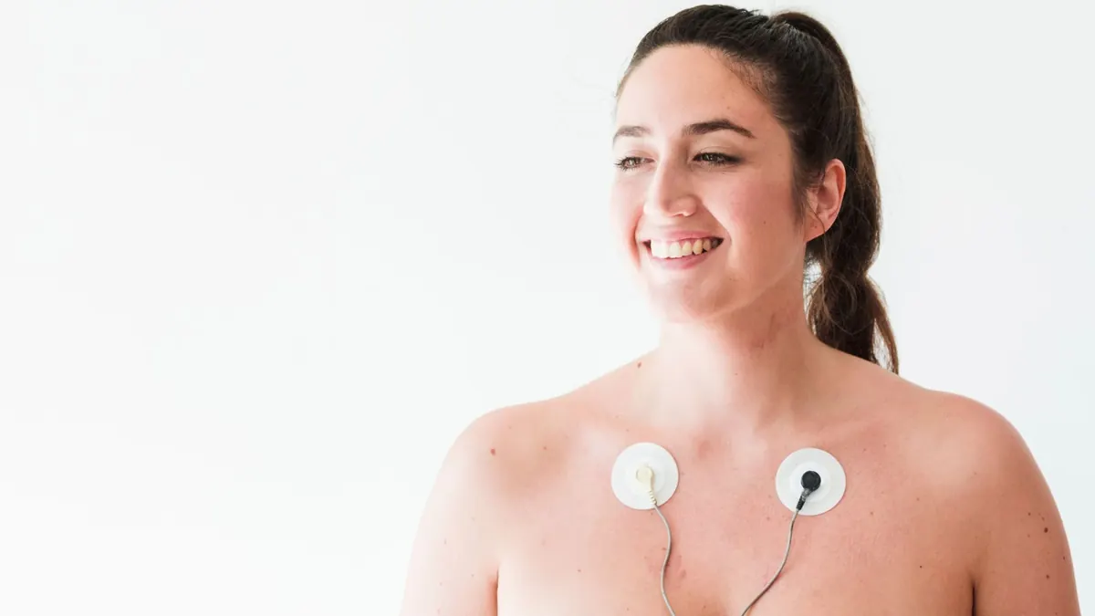 Mulher jovem sorrindo com eletrodos no corpo