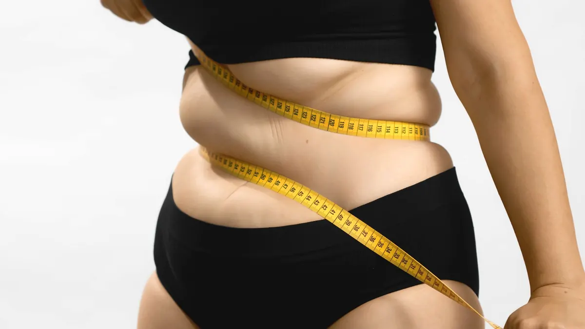 Mulher acima do peso insatisfeita com o corpo e fita métrica